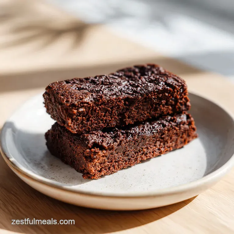 Glossy, dark chocolate protein bar slice on a white plate with a dusting of cocoa powder for an elegant dessert.