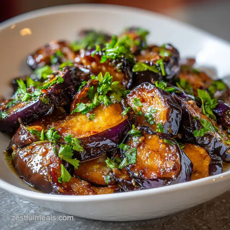 Elegant plate of tender roasted eggplant with fragrant garlic, drizzled with olive oil and garnished with fresh, vibrant p...
